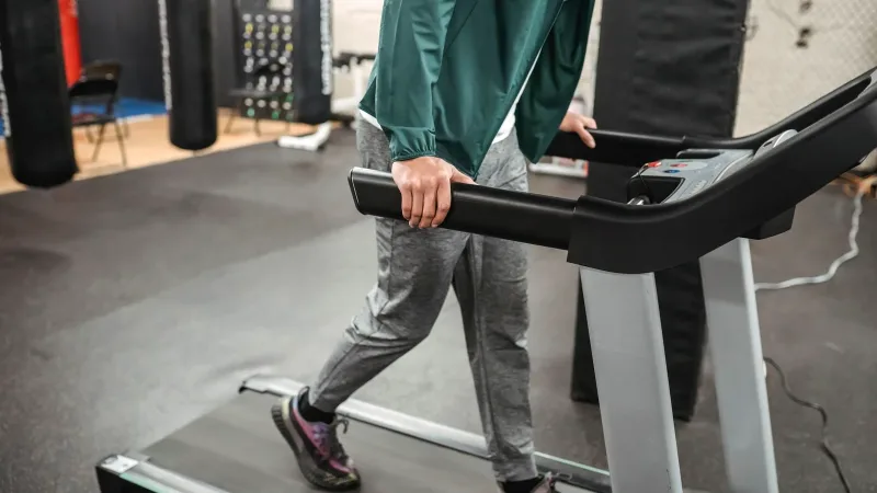 Spor salonunda yürüyüş bandında yürüyen kişi